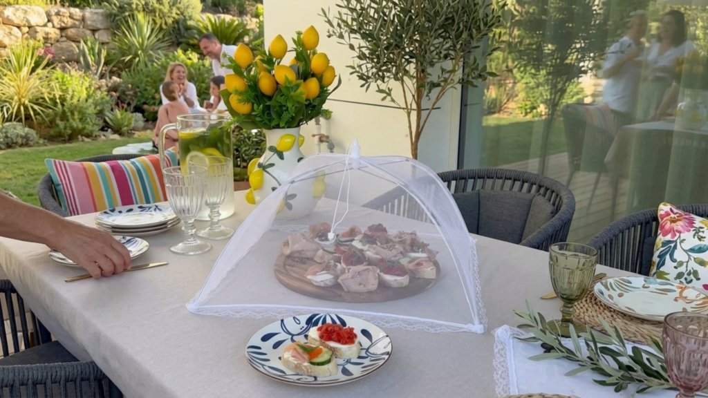 Pop-up mesh food cover protecting a platter of food during an outdoor meal.